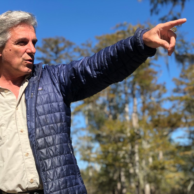 a man wearing a suit and tie holding his hand up