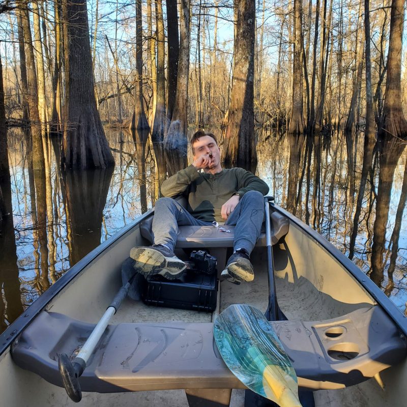 a person sitting on a bench next to a forest